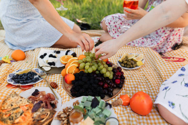 istock Unrecognizable female hands take grapes from a plate at a picnic on a sunny day 1605392068