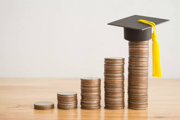 istock Coins stacked graph growing up and graduation hat on wooden table background copy space. 1605396903