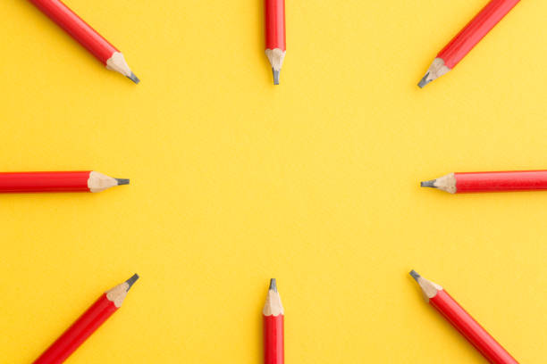 istock Flat lay of red pencils around border frame on yellow background. 1605396904
