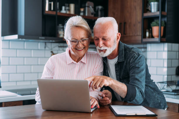 старшая пар�а управляет бюджетом и оплачивает счета и налоги. - e commerce couple working at home internet стоковые фото и изображения