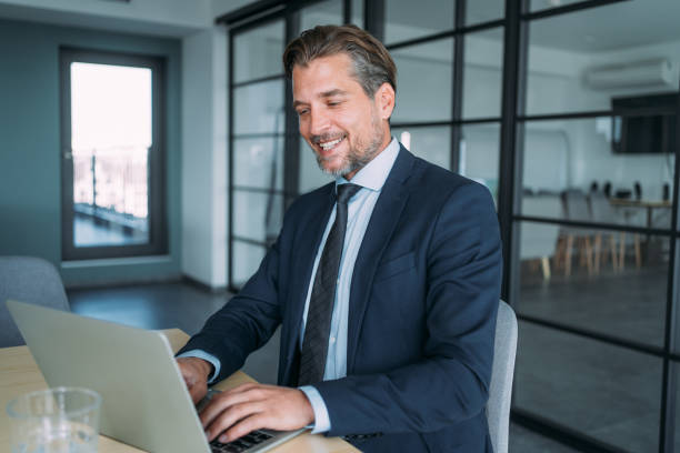 istock Successful businessman in modern office working on laptop. 1605405202
