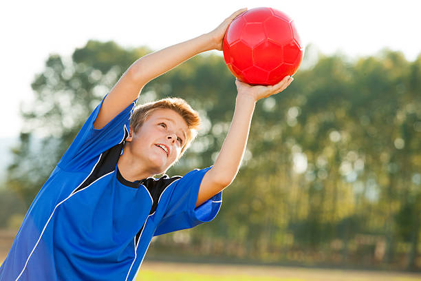Boy standing with goalkeeper gloves on his hands at some old door and waiting for his friend to kick the ball.