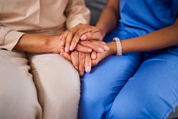 Hands, medical or support with a nurse and patient in a living room for love, trust or care during treatment. Healthcare, empathy and a black woman medicine professional comforting a clinic resident manos, apoyo médico o de apoyo con una enfermera y un paciente en una sala de estar para amor, confianza o cuidado durante el tratamiento. atención médica, empatía y una mujer negra profesional de la medicina consolando a un residente de la clínica