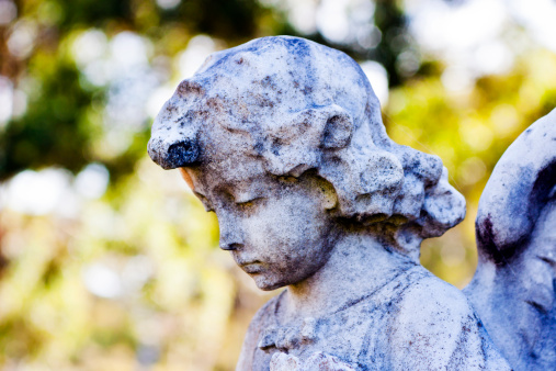Closeup old weathered statue of little angel, full frame horizontal composition with copy space
