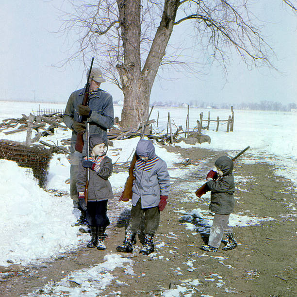 hunting with Grandad 1959 Young boys going hunting with Grandad. Grandad has a Winchester model 12 shotgun, boy on left has Daisy model 25 BB gun, middle boy has Winchester model 67 rifle, boy on right has pop gun. Iowa 1959, scanned film with grain. 20th century style photos stock pictures, royalty-free photos & images