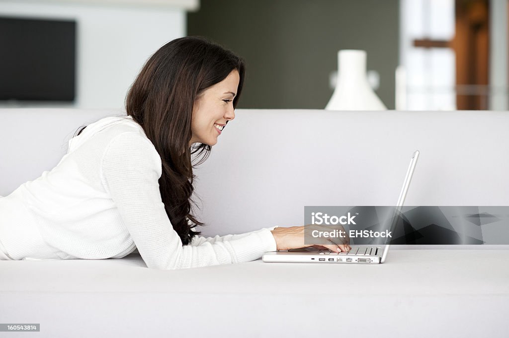 Młoda kobieta relaks w salonie na kanapie z laptopa - Zbiór zdjęć royalty-free (20-29 lat)