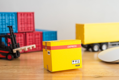 Yellow parcel carton box, cargo shipping containers, forklift, delivery truck, mouse computer on wooden table. E-commerce, online home shopping, import export shipping logistics business, delivering concept.