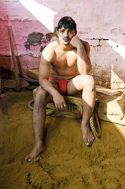 Indian wrestler Muscular build of Indian wrestler sitting at edge of sand filled wrestling ring. Delhi, India. greco stock pictures, royalty-free photos & images