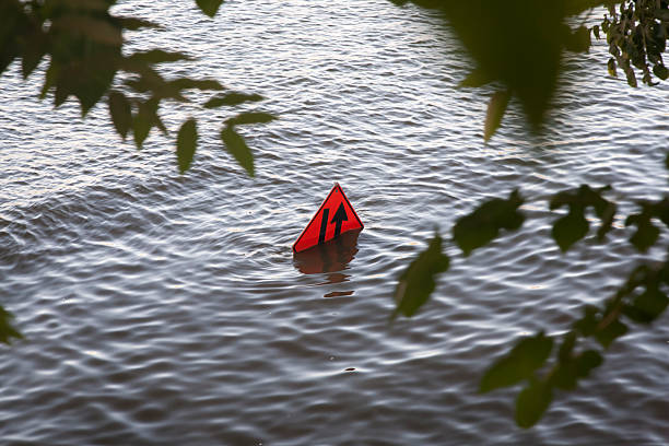 istock orange construction road sign under high flood water & tree 160544428
