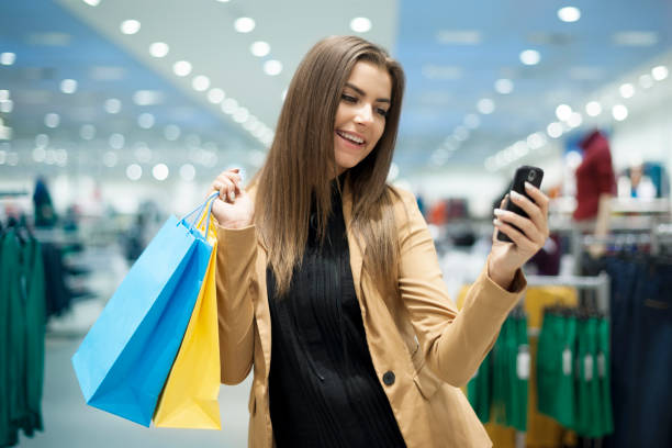 istock Cheerful female shopper texting on mobile phone 160544703