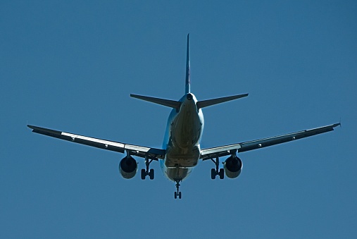 View of the wing and engine of a passenger aircraft and a landing airplane flying in the sky