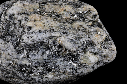 Closeup view of piece of granite rock with crysyals isolated on a black background