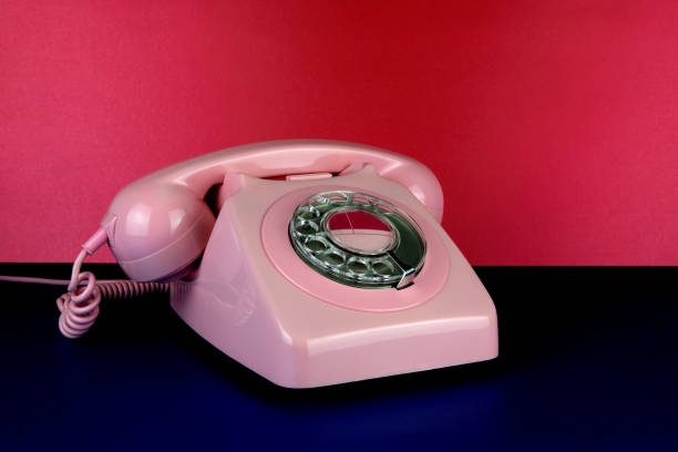 istock Vintage Pink Telephone on a Blue Surface with Red Background 1605467990