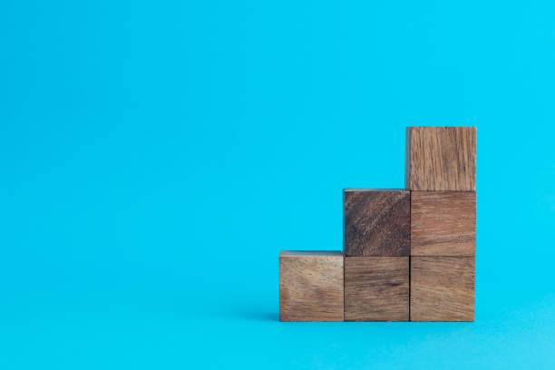istock Wooden cube block stacking as stair or growth chart on blue background. 1605471511