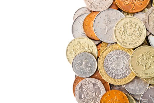 A pile of modern Great Britain (GBP) coins with white copy space on the left side for the designer to use. Main focus is on the top half of the image.