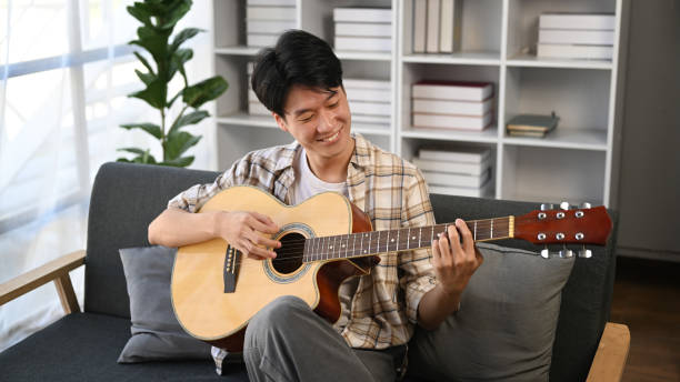 istock A man playing a guitar at home. Domestic life concept. 1605476744