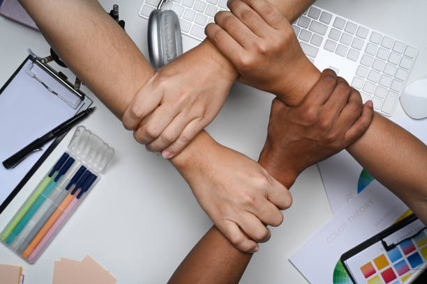 multiracial group hands holding each other wrist on office table.
