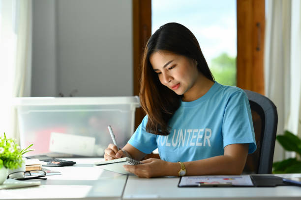 istock Woman volunteer writing on notepad in the office 1605480030