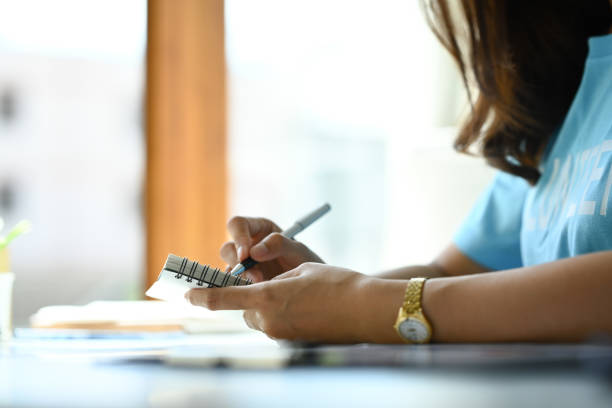 Closeup Woman volunteer writing on notepad in the office.