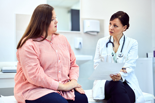A professional female nutritionist talking with an overweight female patient about bad blood results.