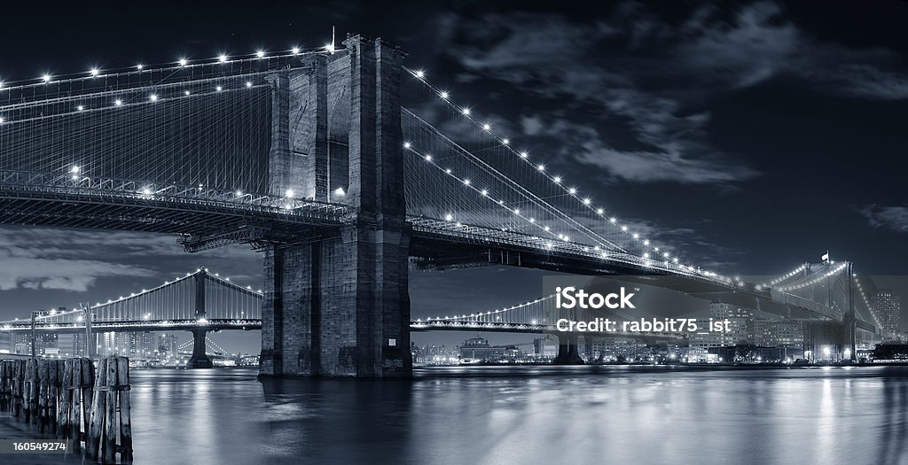 Urban bridge night scene Brooklyn Bridge over East River at night in black and white in New York City Manhattan with lights and reflections. Architecture Stock Photo