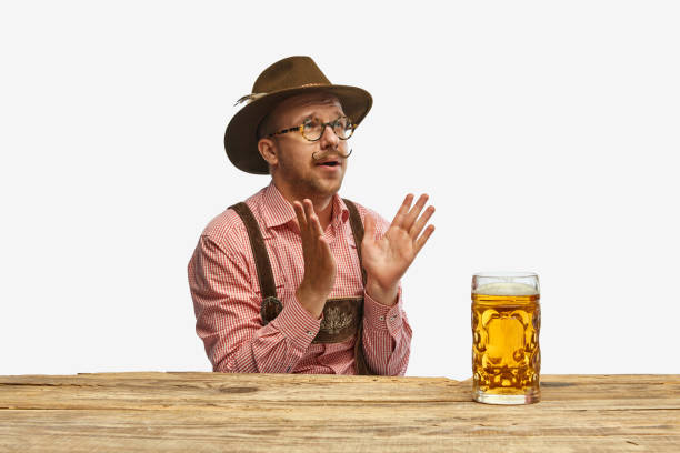 最高の飲み物。伝統的なドイツの衣装を着た帽子をかぶったバイエルンの口ひげの男と巨大なグラスのビール。オクトーバーフェストのコンセプト - beer glass mustache beer color image ストックフォトと画像
