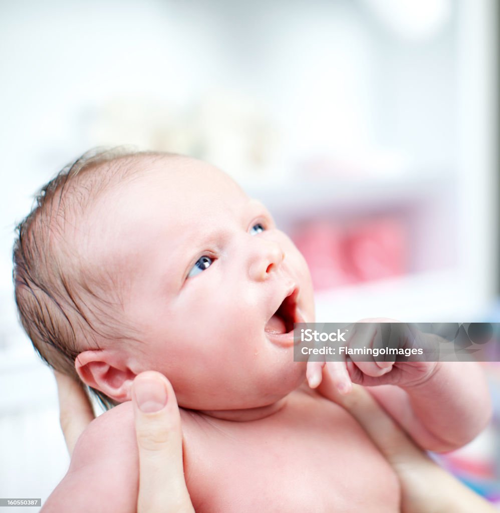 Newborn baby with look of wonderment Adorable beautiful newborn baby cradled in its mothers hands looking up with a look of wonderment Adult Stock Photo