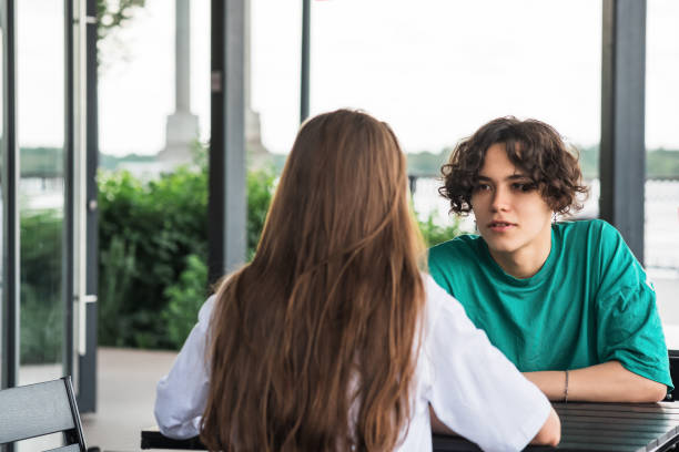 istock young couple talking while sitting at a street food table 1605504904