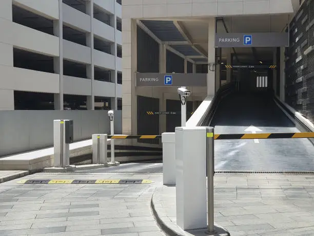 Photo of Entrance to underground, multi-storey Parking. Automatic barrier with video camera. Signpost parking. Pointer