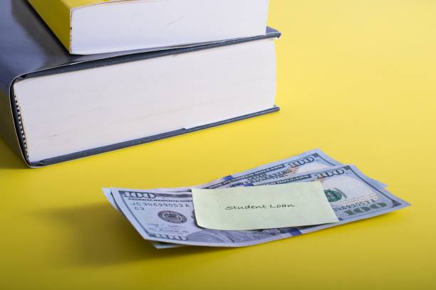 istock ‘Student Loan’ note posted to two one hundred dollar bills textbooks in background 1605540839