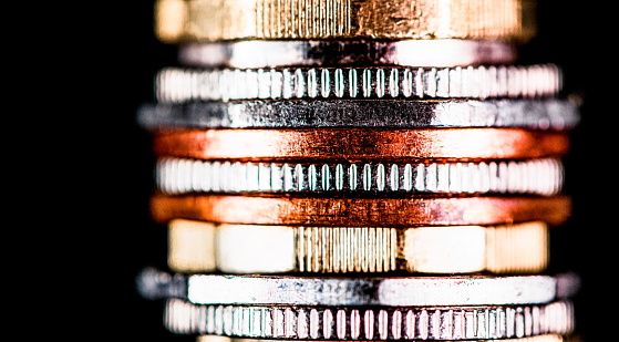 Close-up of a stack of coins, photographed against a black background.