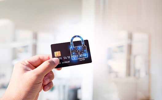 Close up of man hand holding credit or debit card with padlock, protection of financial transactions, copy space, Financial security technology concept.