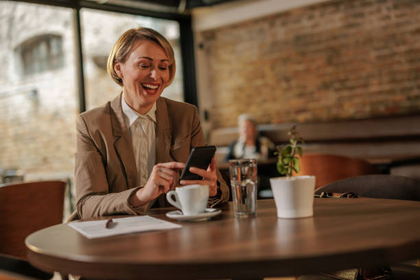 istock Joyful female entrepreneur using mobile phone in cafe. 1605568209