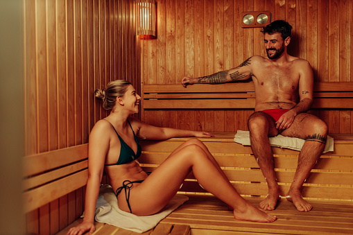 Young couple is relaxing in the sauna, resting, caressing and looking at each other
