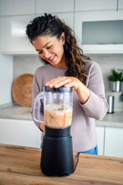 istock Woman preparing a smoothie in her kitchen at home 1605581527