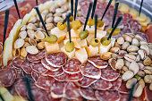 A tray with delicious salami, slices of chopped ham and olives, pistachios, sir. Meat dish on the festive table