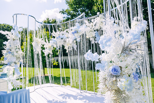 Outdoor wedding ceremony setup, wedding arch decorated with pastel white blue flowers