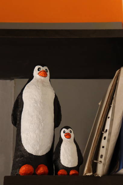 istock Two Paper Mache Penguin in a shelf aside with Some Folders 1605605499