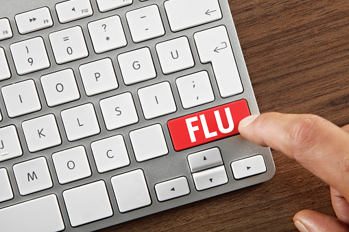 Man pushing ”Flu” key on computer keyboard.