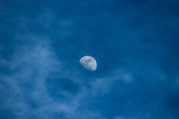 istock Half Moon in Daytime Blue Sky with Puffy Clouds 1605619107