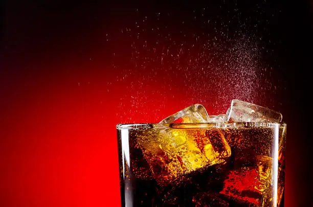 Photo of Glass cup of iced cola on red background