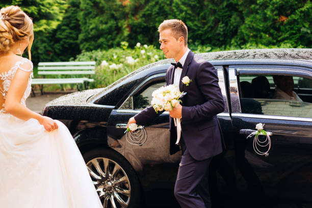 istock the groom opens before bride door to a chic black car 1605625122
