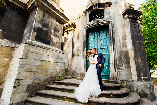 elegant newlyweds want to kiss on a background of beautiful building