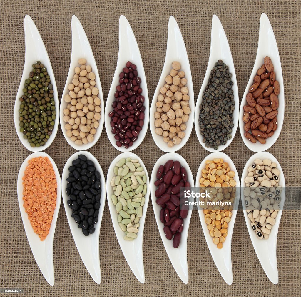 Health Food Pulses vegetable selection of peas, beans and lentils in white porcelain bowls over hessian background. Adzuki Bean Stock Photo