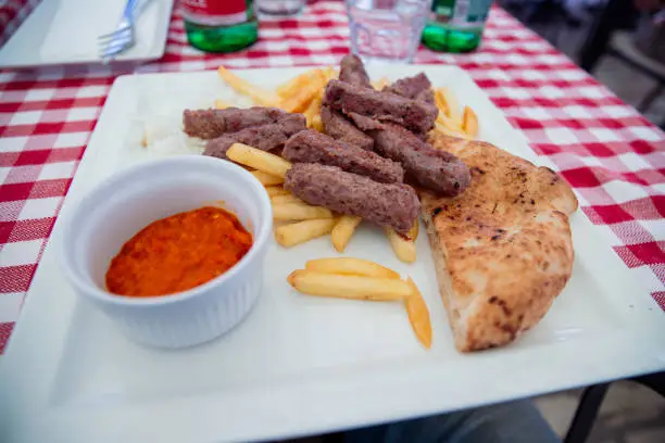 Cevapcici served with fried potatoes, bread and a red sauce, typical Balkan cuisine