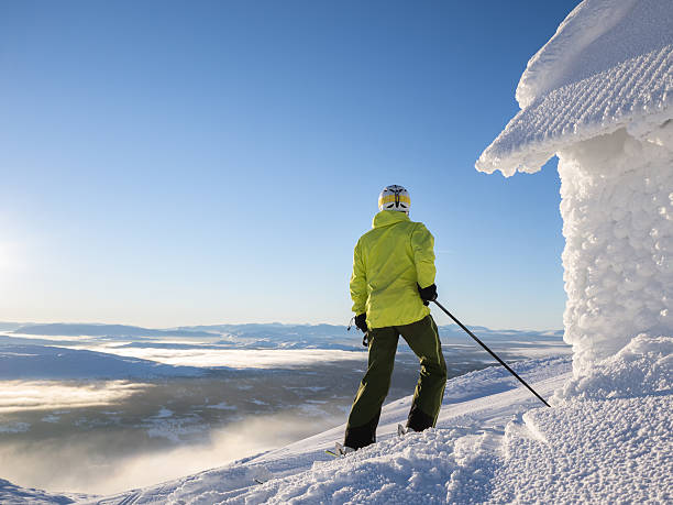 Skier looking out over partly cloud covered valley stock photo