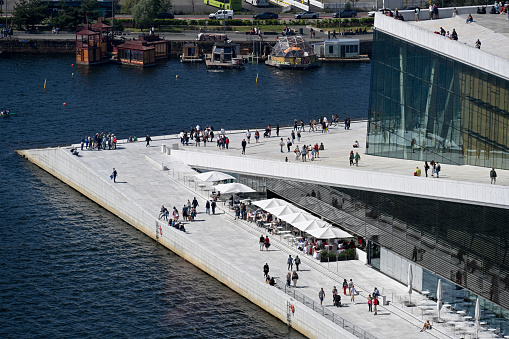 Oslo, Norway, July 5, 2023 - locals and tourists walk across the marble roof of the Oslo Opera House (Norwegian: Operahuset).