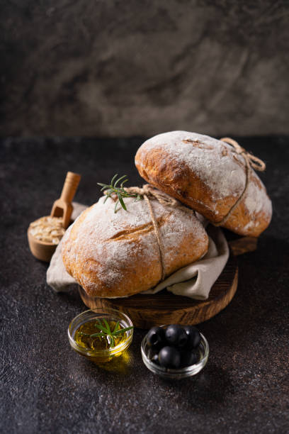 istock Fresh organic homemade artisan ciabatta bread on dark rustic background. sourdough bread 1605715801
