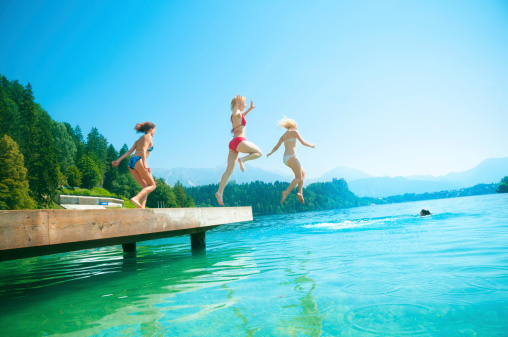 Teenage girls jumping from pier in the lake. Bled. Slovenia