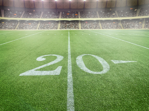 Wide angle view of a20 yard line in a football stadium with fulllbleachers